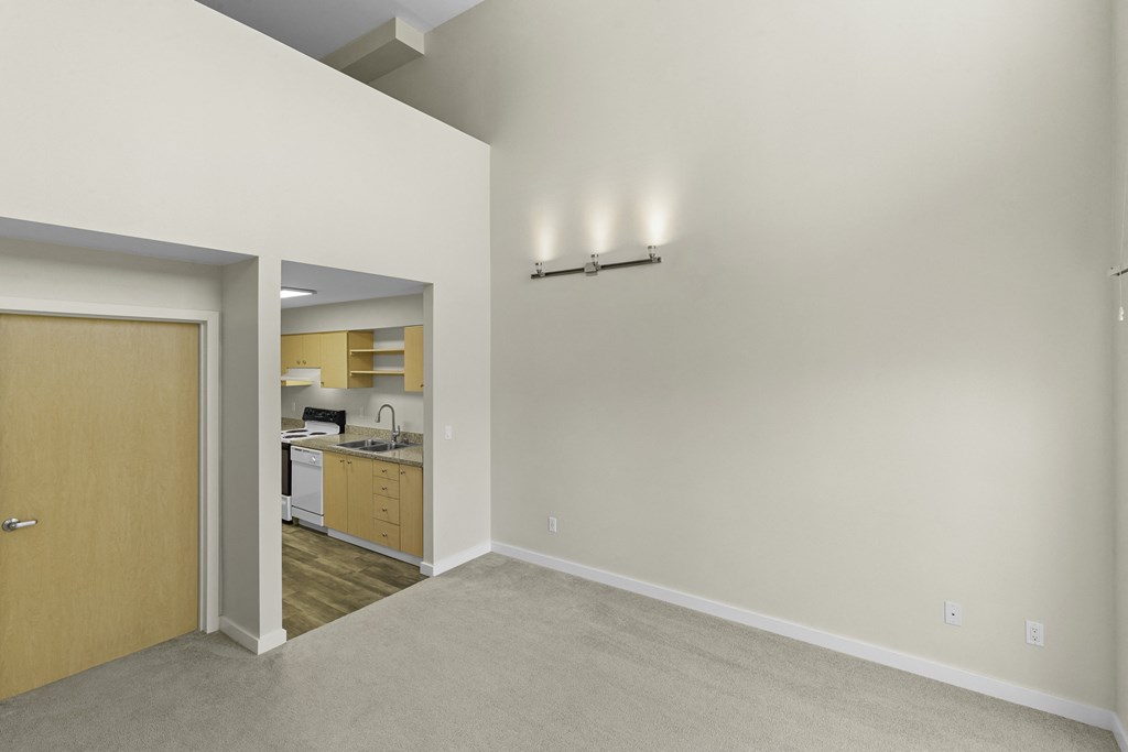 Generous Living Space with Sconce Lighting, a Kitchen View in the Background, and Second Floor Generous Living Space with Sconce Lighting, a Kitchen View in the Background, and Second Floor at Sir Gallahad Apartment Homes, WA 98004